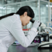Asian female looking through microscope in lab